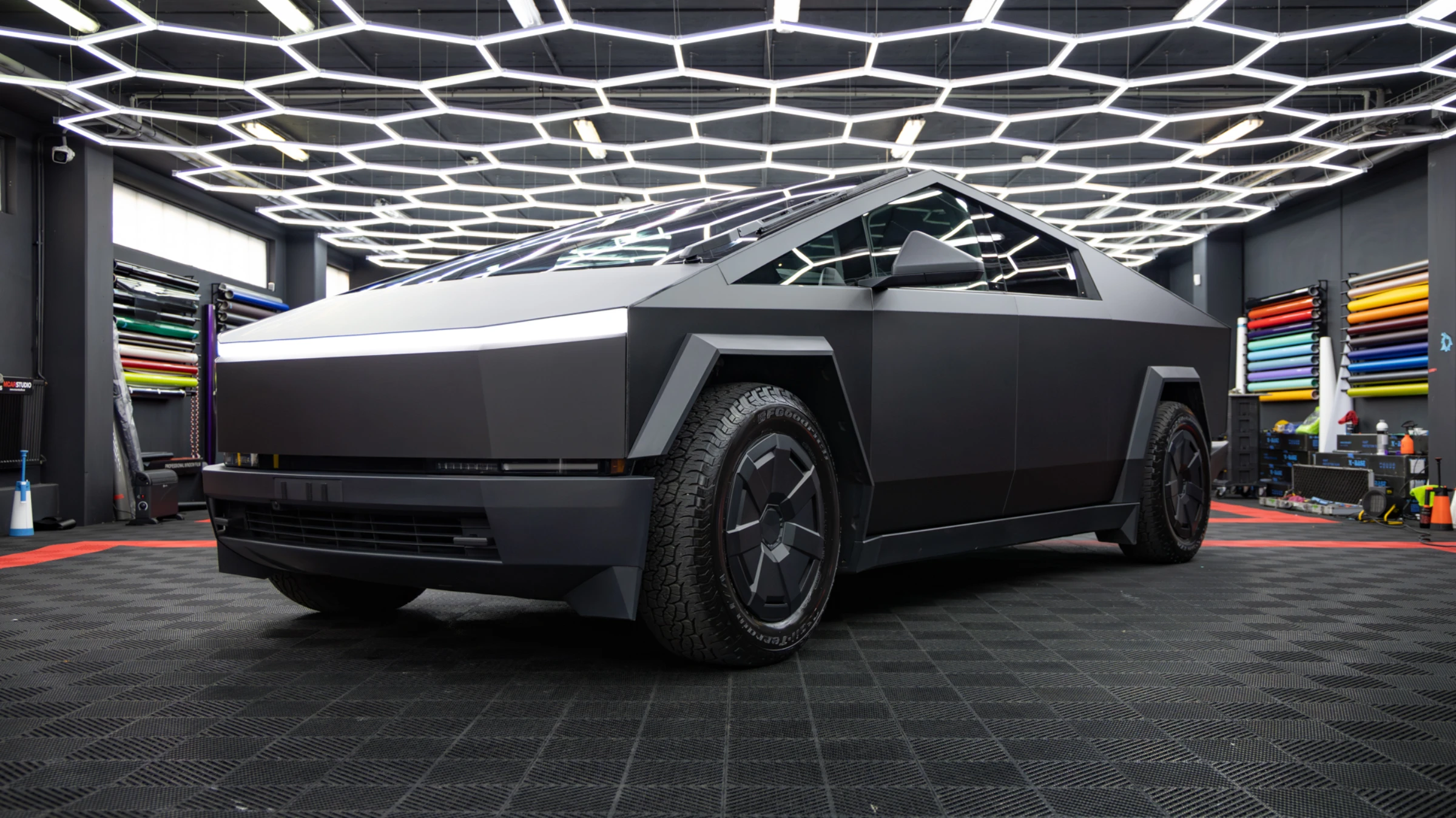 A Cybertruck under the hex lighting of the MCarStudio workshop